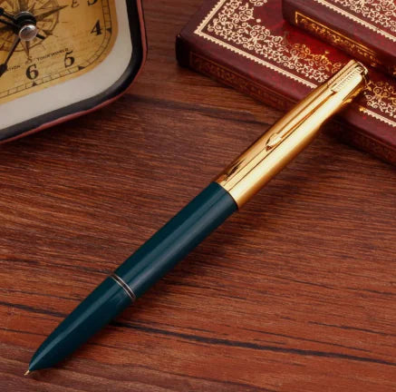 Gold and green pen on a wooden surface with an ornate book and clock in the background