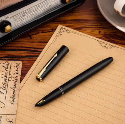 Black fountain pen on a wooden desk with a vintage radio and letter in the background