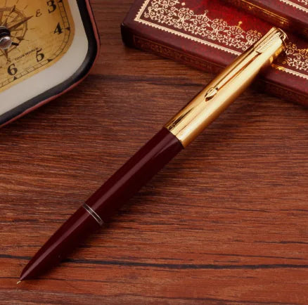 Maroon pen with gold accents on a wooden surface