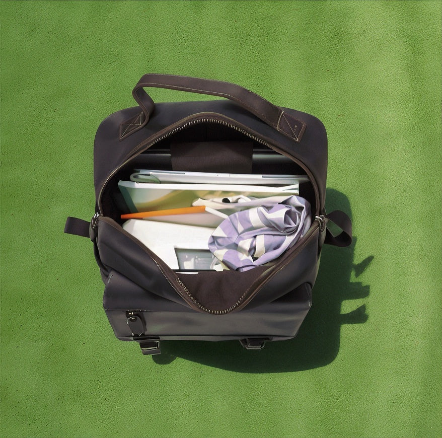 Open black bag with items on a green background